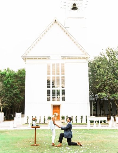 young man proposing to a young woman in front of the Chapel at Seaside